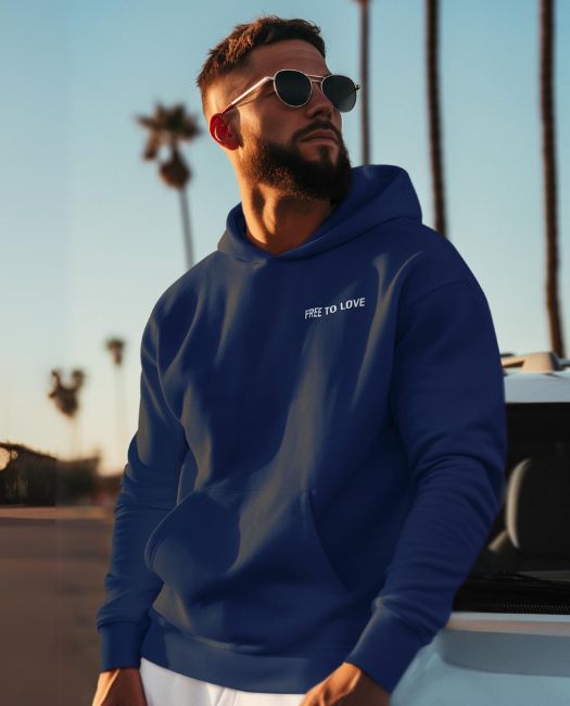 Man wearing our navy "free to love" cosy Hoodie outside, near a car ant with palm trees behind