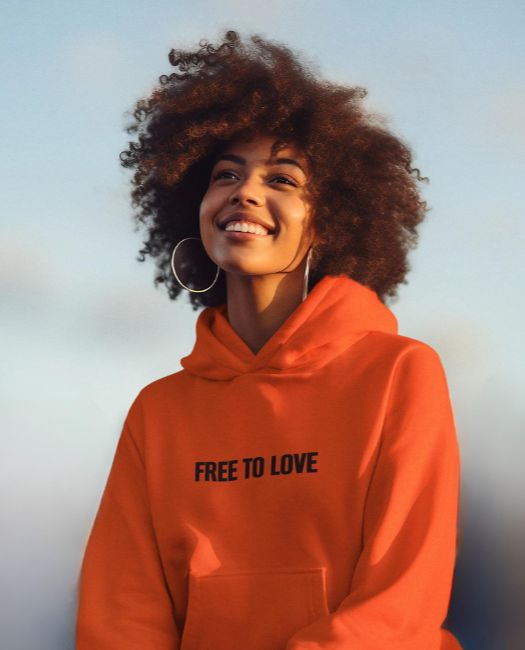 Young smily woman wearing our 100% organic coton "free to love" orange hoodie